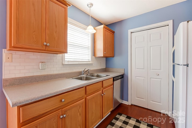 kitchen with a sink, stainless steel dishwasher, freestanding refrigerator, decorative backsplash, and decorative light fixtures