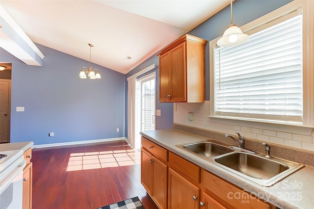 kitchen featuring hanging light fixtures, dark wood-style floors, vaulted ceiling, and a sink