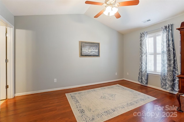 spare room with lofted ceiling, ceiling fan, wood finished floors, visible vents, and baseboards