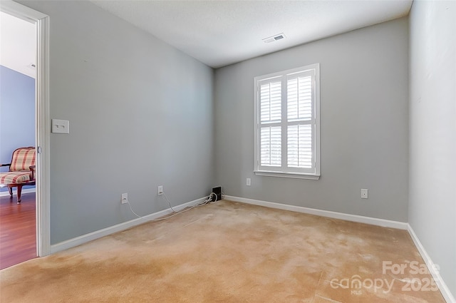 unfurnished room with visible vents, light carpet, and baseboards