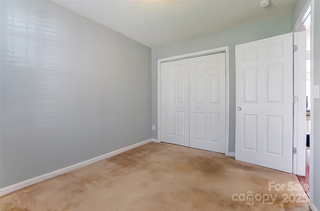 unfurnished bedroom with light carpet, baseboards, and a closet