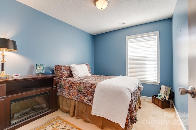 bedroom with visible vents, baseboards, a textured ceiling, and light colored carpet