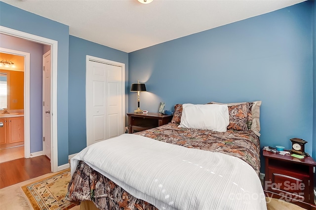 bedroom with a sink, a closet, wood finished floors, and baseboards