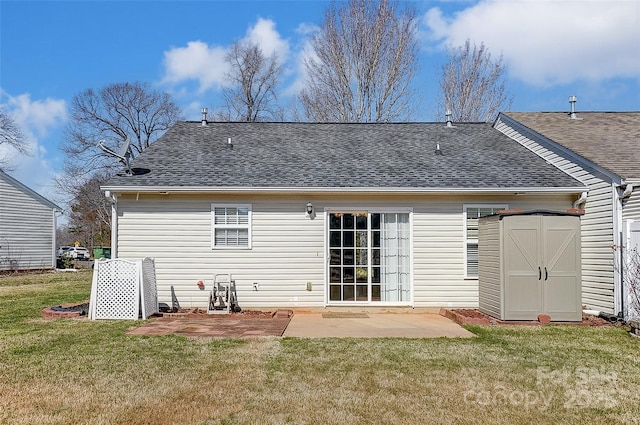 rear view of property featuring a storage shed, a patio, a shingled roof, and a lawn