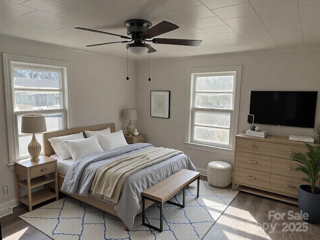 bedroom with wood finished floors, a ceiling fan, and baseboards