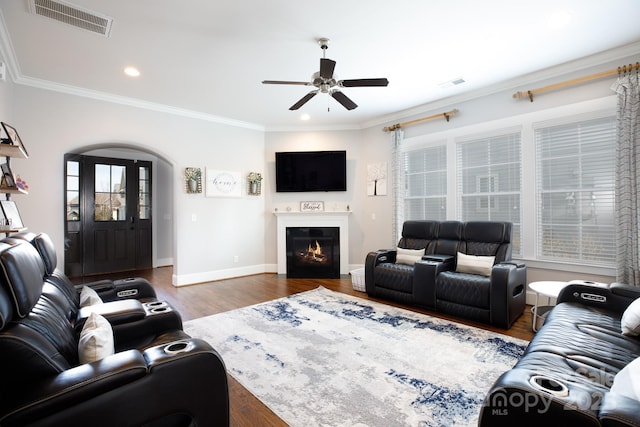 living area with visible vents, crown molding, and wood finished floors