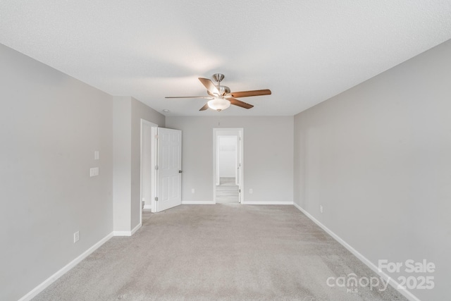 unfurnished room with a textured ceiling, baseboards, a ceiling fan, and light colored carpet