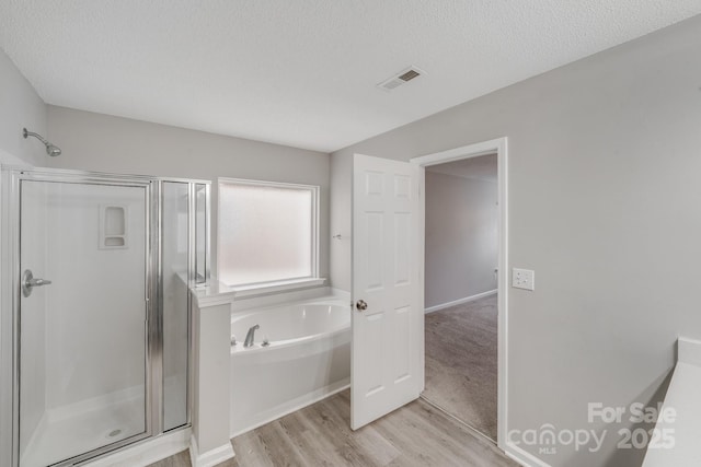 bathroom with a garden tub, a textured ceiling, a shower stall, and visible vents