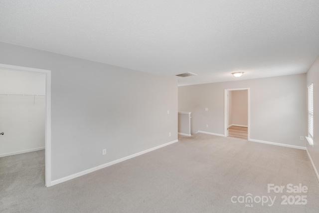 spare room featuring light colored carpet, visible vents, and baseboards