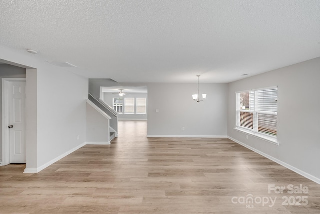 interior space featuring stairway, baseboards, a textured ceiling, and light wood finished floors