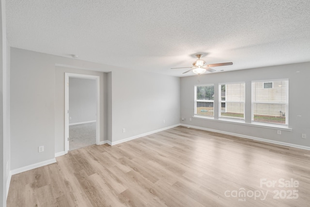 unfurnished room with light wood-style flooring, a textured ceiling, baseboards, and a ceiling fan