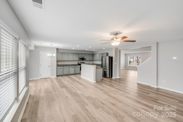 kitchen featuring stainless steel appliances, a kitchen island, open floor plan, hanging light fixtures, and gray cabinets