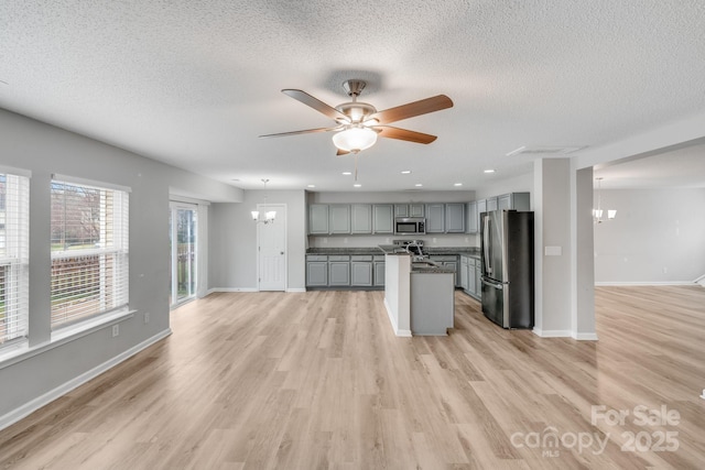 kitchen with a center island, dark countertops, gray cabinets, appliances with stainless steel finishes, and open floor plan