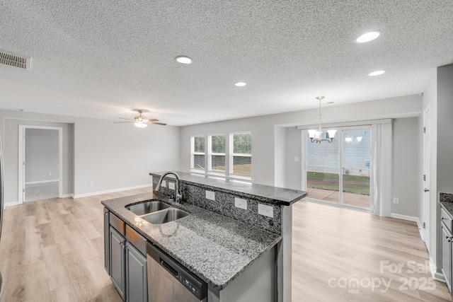 kitchen with dishwasher, a center island with sink, visible vents, and a sink