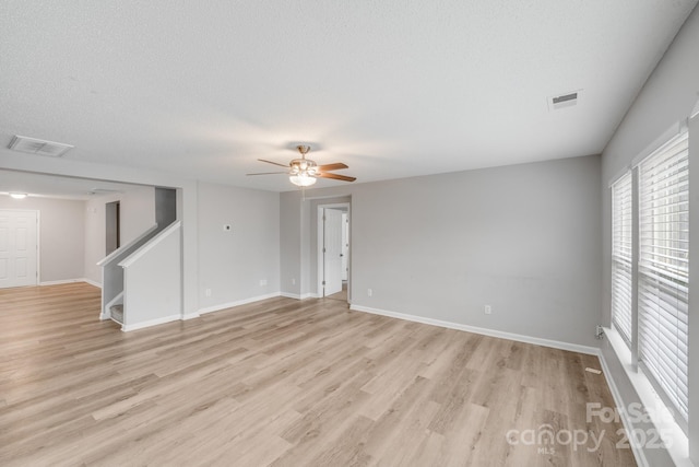 empty room featuring a textured ceiling, ceiling fan, light wood-type flooring, and visible vents