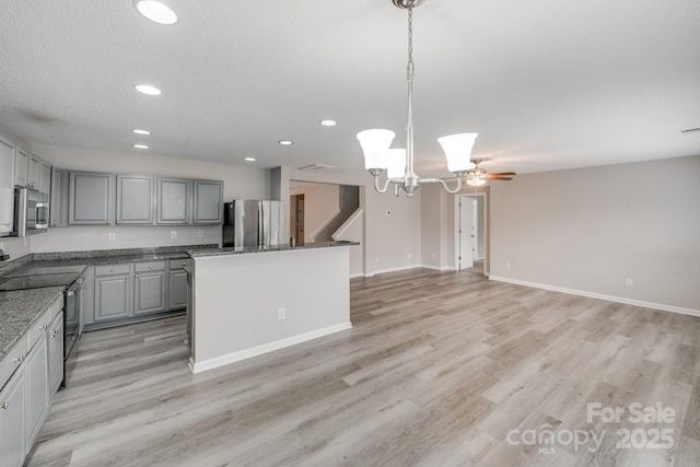 kitchen featuring decorative light fixtures, light wood-style flooring, gray cabinetry, appliances with stainless steel finishes, and a kitchen island