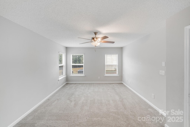 empty room featuring light carpet, ceiling fan, a textured ceiling, and baseboards