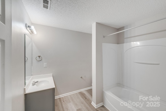 full bathroom featuring shower / bath combination, vanity, a textured ceiling, and wood finished floors