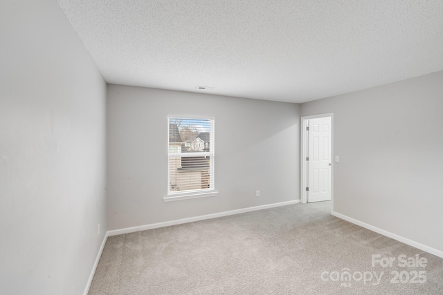 carpeted empty room with a textured ceiling, visible vents, and baseboards