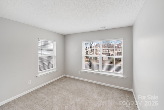 unfurnished room with baseboards, visible vents, a textured ceiling, and light colored carpet