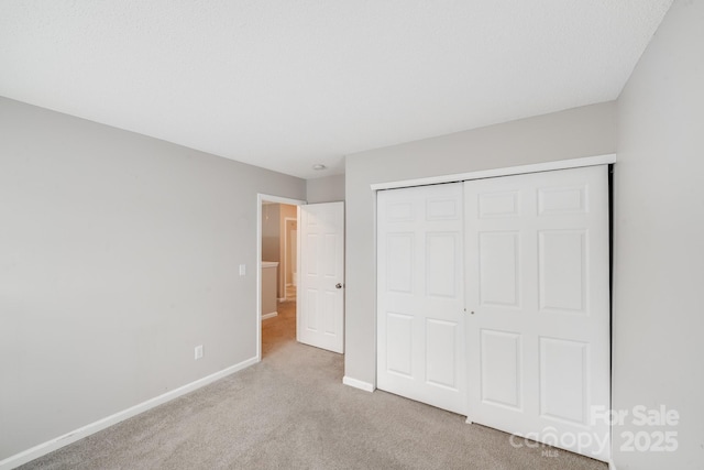 unfurnished bedroom with light carpet, baseboards, and a closet