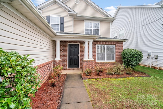 property entrance with a yard and brick siding