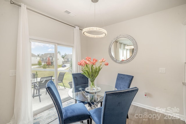 dining space featuring wood finished floors, visible vents, and baseboards