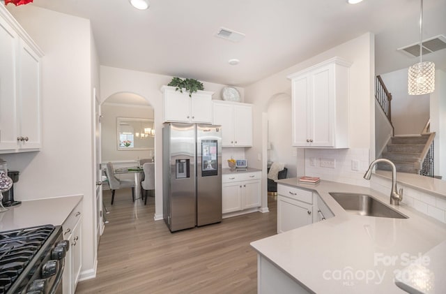 kitchen featuring visible vents, arched walkways, light countertops, stainless steel refrigerator with ice dispenser, and a sink