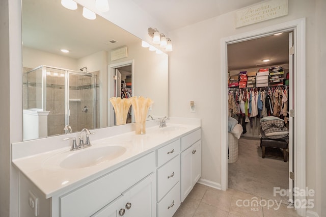 bathroom with a stall shower, tile patterned flooring, a spacious closet, and a sink