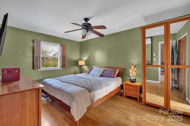 bedroom featuring french doors, light wood-type flooring, and a ceiling fan