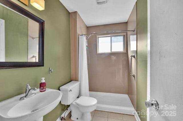 bathroom featuring a stall shower, a sink, toilet, and tile patterned floors