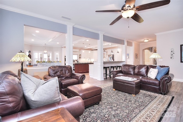 living room with light wood-type flooring, visible vents, arched walkways, and ornamental molding