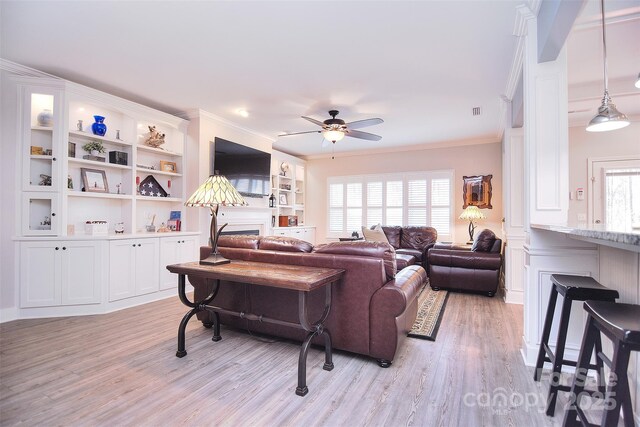 living area with light wood-style flooring, visible vents, ornamental molding, and a ceiling fan