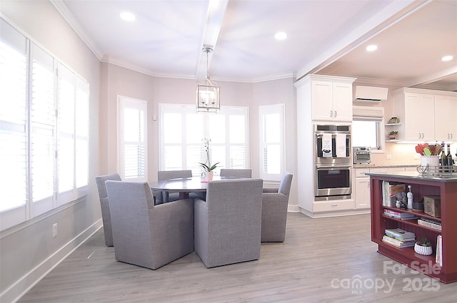 dining room featuring baseboards, light wood finished floors, a wall unit AC, and crown molding