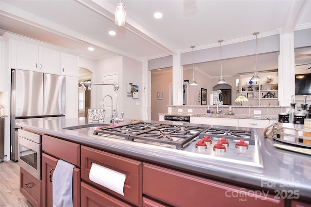 kitchen featuring decorative light fixtures, stainless steel appliances, light wood-style flooring, ornamental molding, and white cabinetry