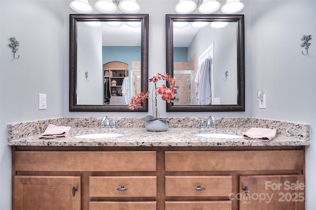 full bathroom with double vanity, a sink, and a shower with shower door