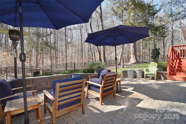 view of patio featuring an outdoor hangout area, a wooded view, and fence