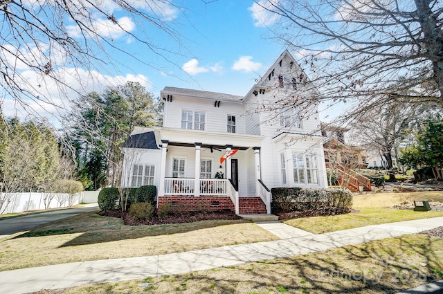 view of front facade featuring covered porch, ceiling fan, fence, and a front lawn