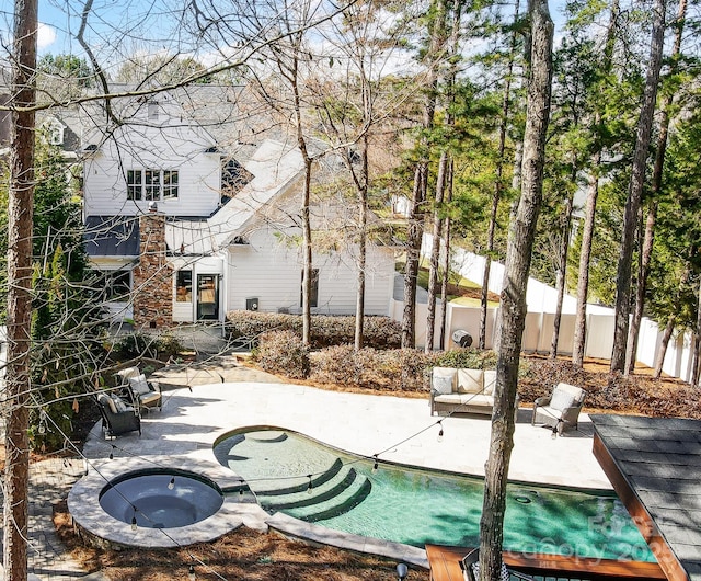 view of pool featuring a patio area, fence, and an in ground hot tub