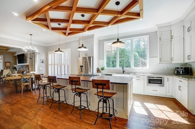 kitchen with coffered ceiling, a sink, stainless steel refrigerator with ice dispenser, a center island, and dark wood finished floors