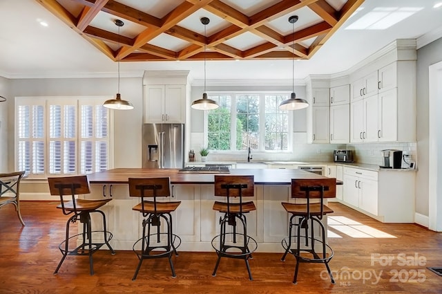 kitchen with coffered ceiling, stainless steel refrigerator with ice dispenser, decorative backsplash, a center island, and dark wood finished floors