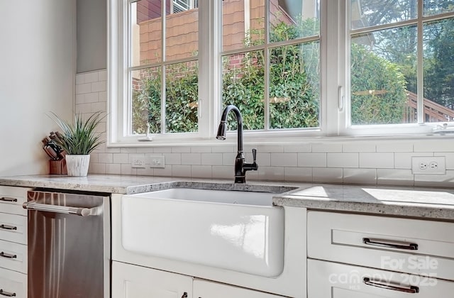 kitchen featuring dishwasher, white cabinetry, decorative backsplash, and a sink