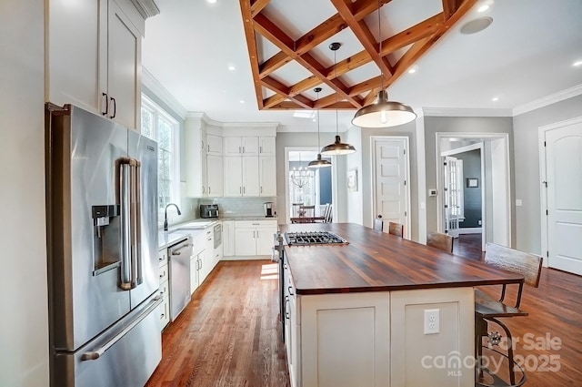 kitchen with premium appliances, butcher block counters, a kitchen island, wood finished floors, and coffered ceiling