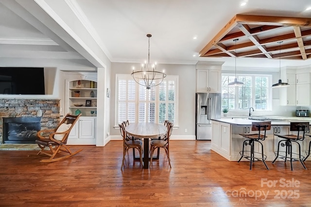 dining area featuring baseboards, coffered ceiling, beamed ceiling, wood finished floors, and a stone fireplace