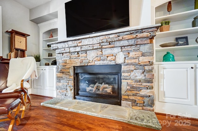 interior details with a fireplace, built in features, and wood finished floors