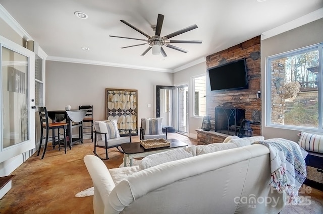 living area with ornamental molding, a fireplace, baseboards, and a ceiling fan