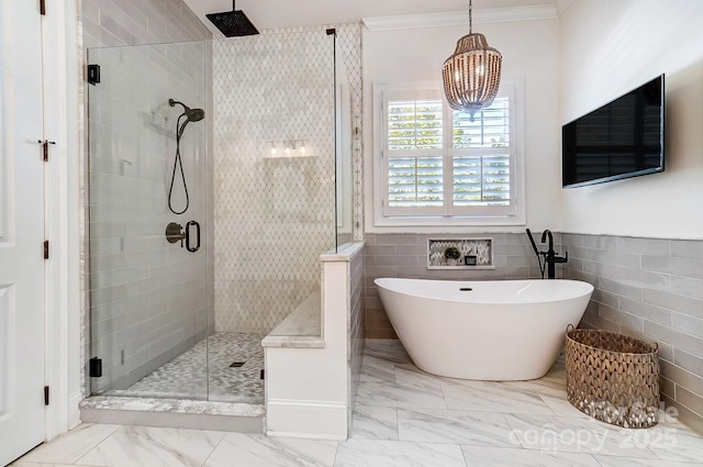 full bathroom with a stall shower, ornamental molding, marble finish floor, a freestanding tub, and tile walls