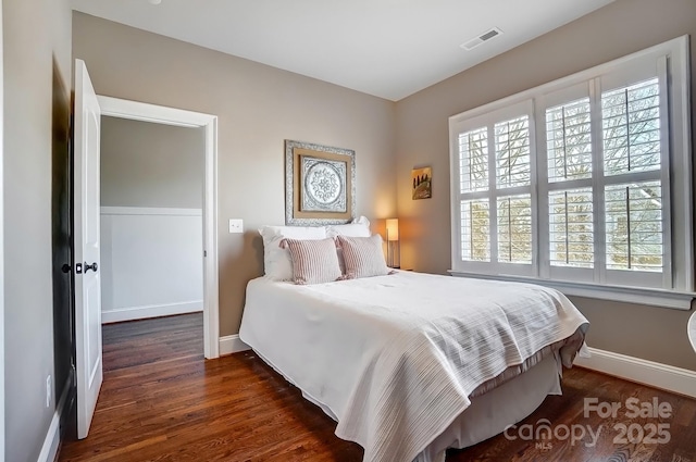 bedroom featuring baseboards, visible vents, and wood finished floors