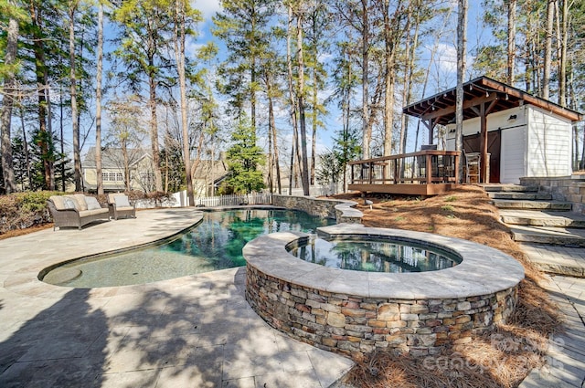 view of swimming pool featuring a pool with connected hot tub, a patio area, and a deck