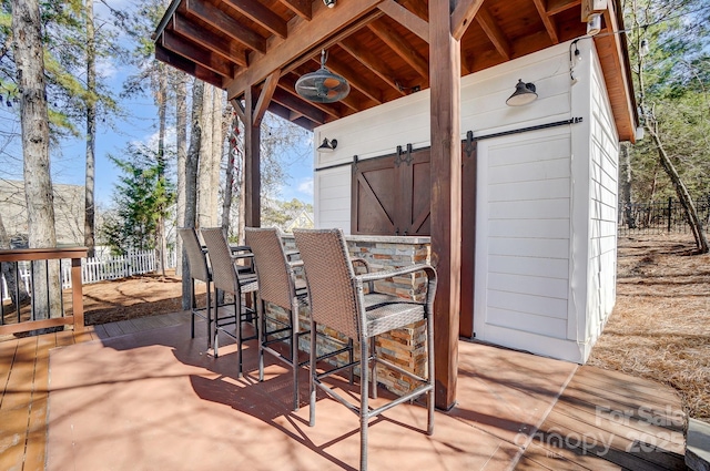 view of patio with outdoor dry bar and fence